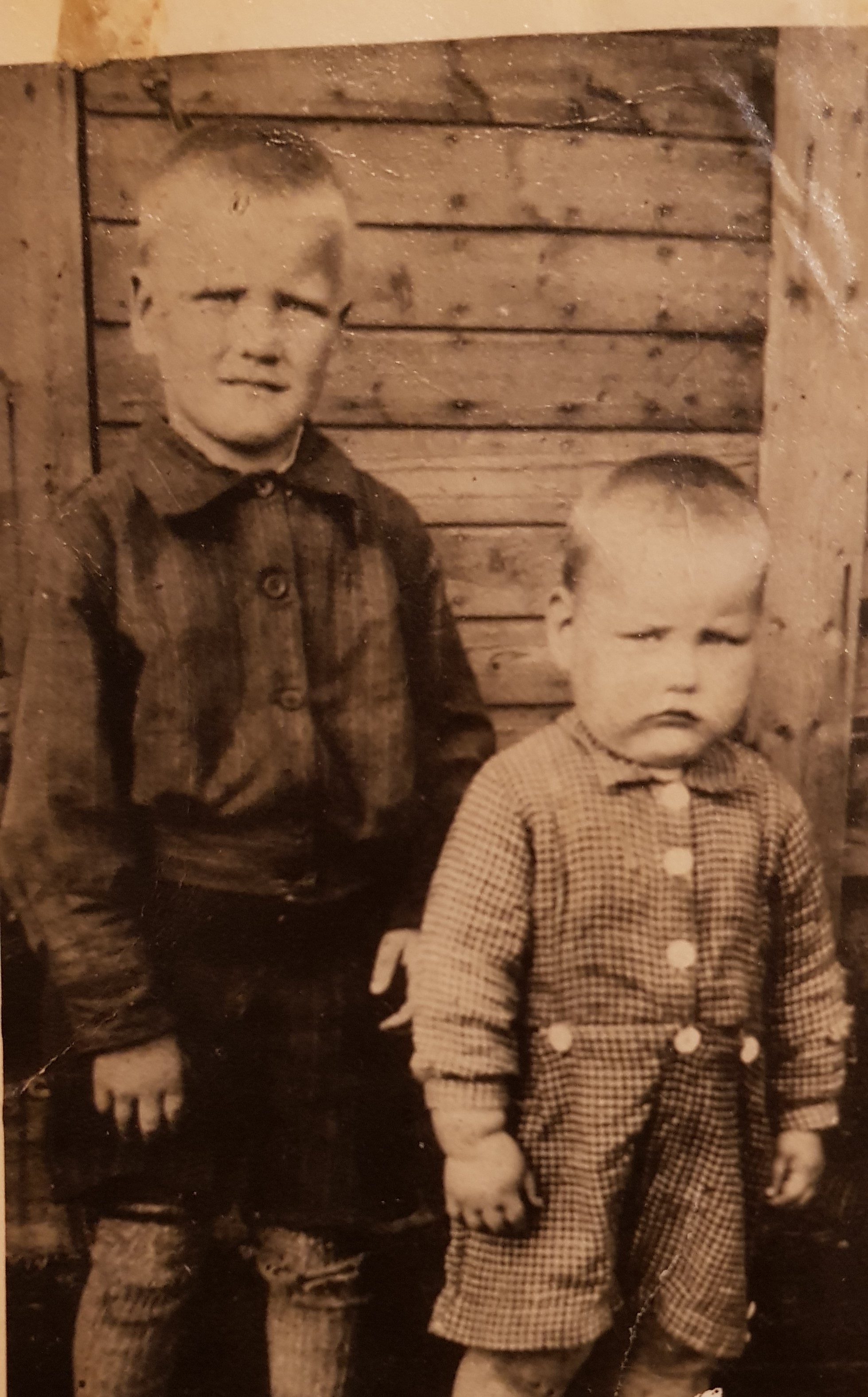 vanhassa valokuvassa kaksi poikaa seisoskelee